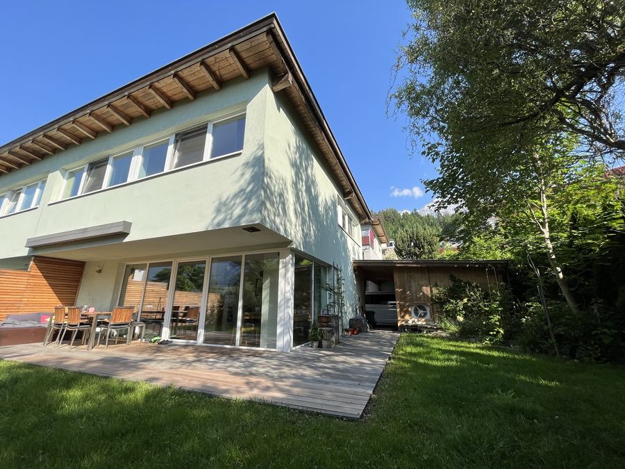 Wohnhaus von der Gartenseite mit Terrasse, im Hintergrund der Aufstellort der Wärmepumpe